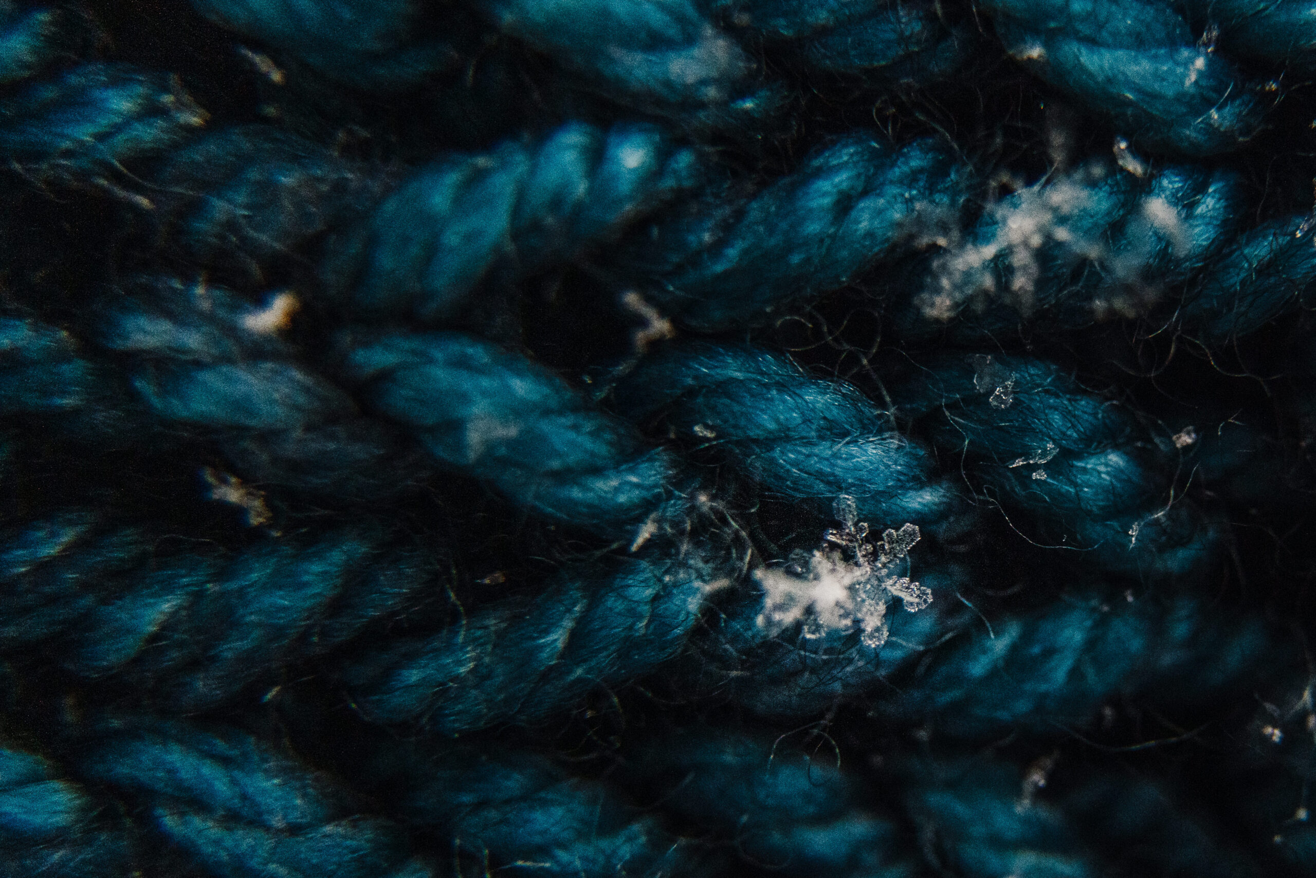 Macro image of snowflake captured on blue fabric cloth.