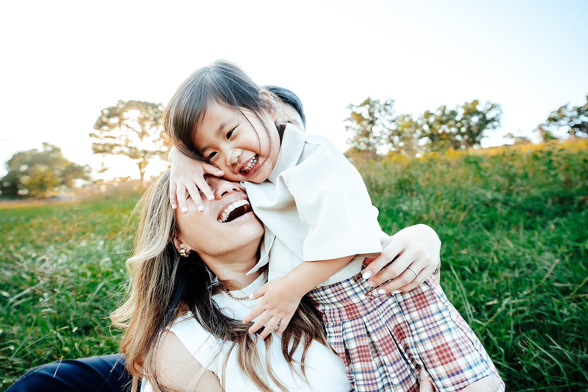 mother and daughter laughing while daughter climbs on the mother