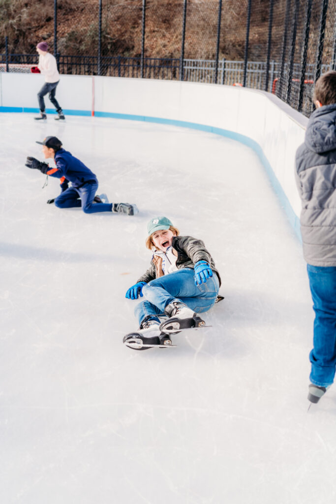 Child laughing after falling while ice skating at Bear Mountain outdoor rink.