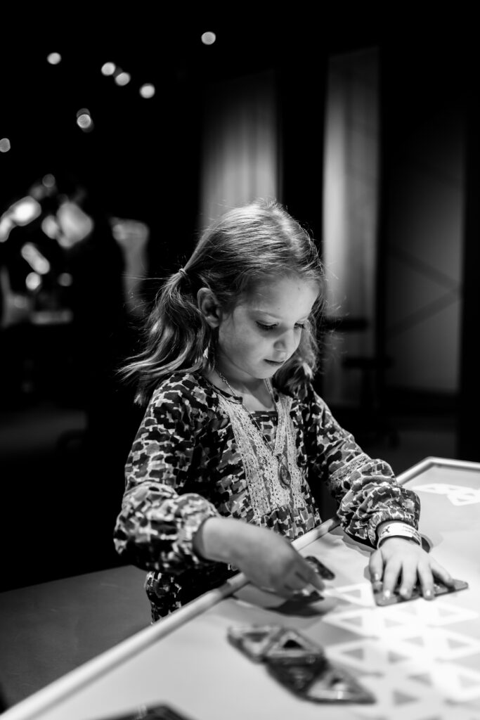 Child concentrating while using an interactive educational exhibit at Liberty Science Center.