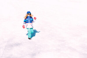 Child in colorful snowsuit walking across snowy slopes at Mount Peter.